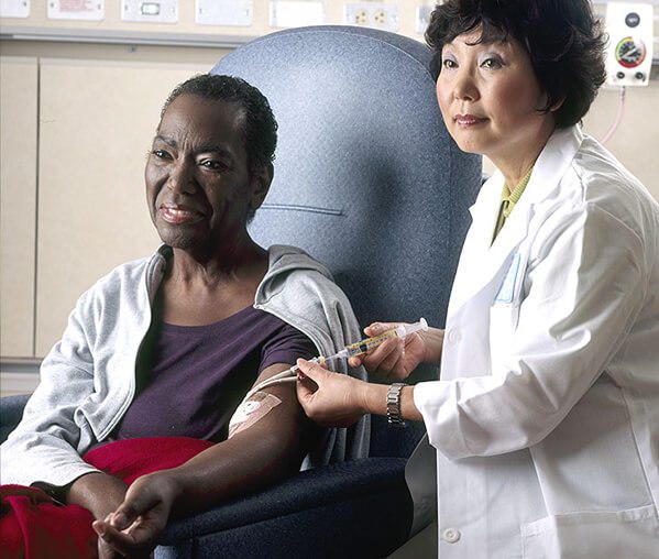 Une infirmière administre une perfusion de chimiothérapie à une patiente. Photographie documentaire du National Cancer Institute.
