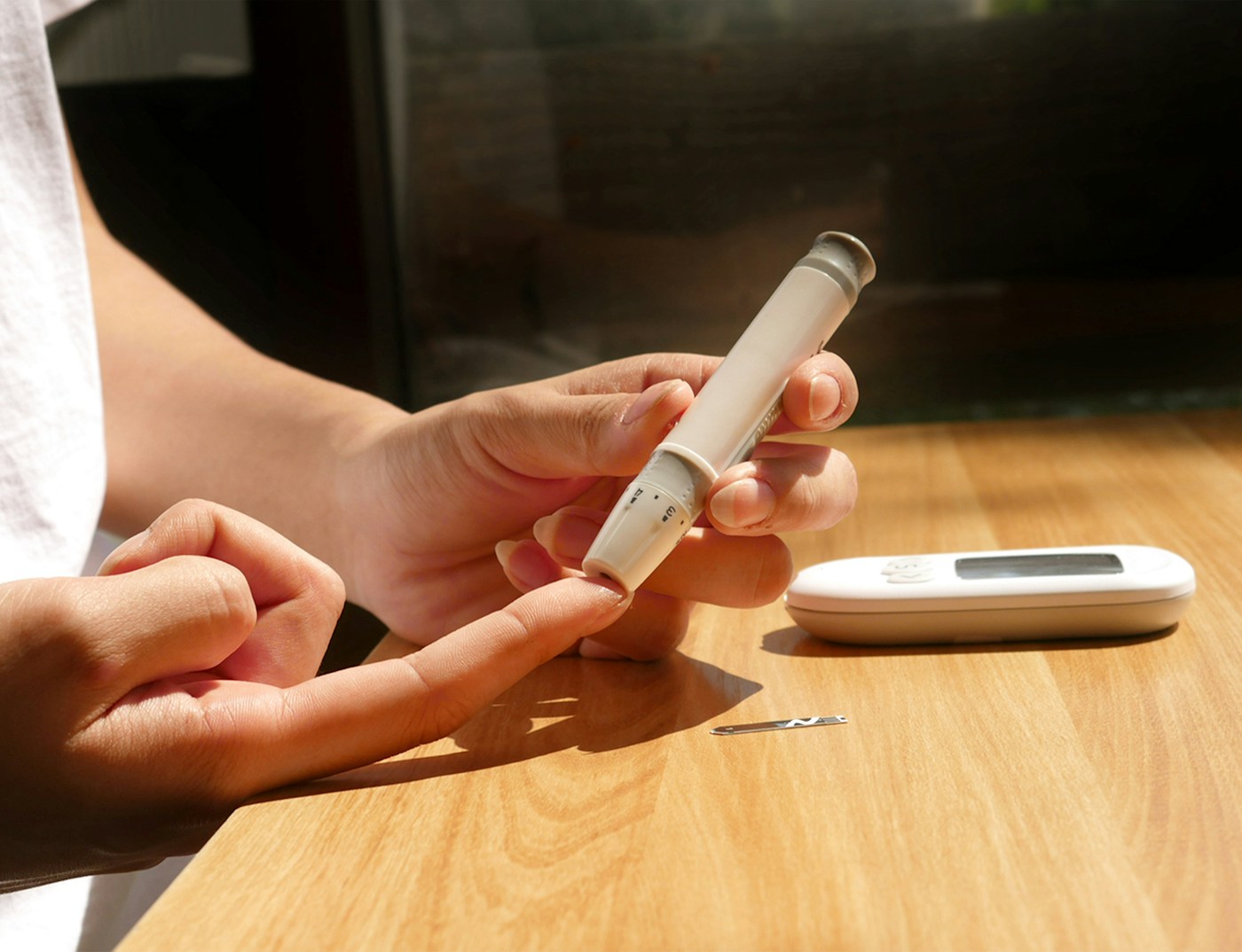 Personne utilisant un dispositif de suivi de la glycémie et un téléphone. Photographie d’illustration, sans résultat interprété.