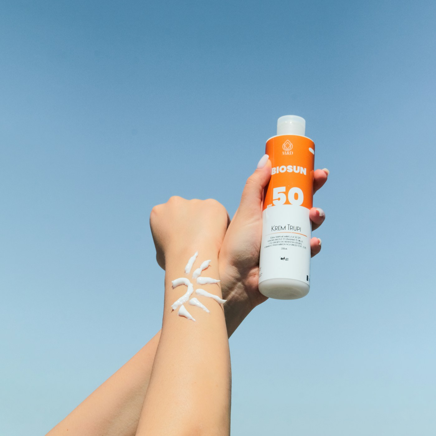 Produit de protection solaire tenu dans une main. Photographie d’illustration, sans recommandation de marque.
